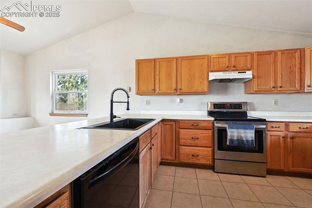 Image 10 of 50: Kitchen featuring electric stove, light countertops, dishwasher, vaulted ce