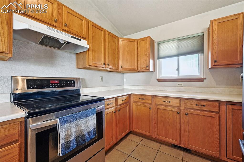 Image 12 of 50: Kitchen with stainless steel electric range, under cabinet range hood, brow