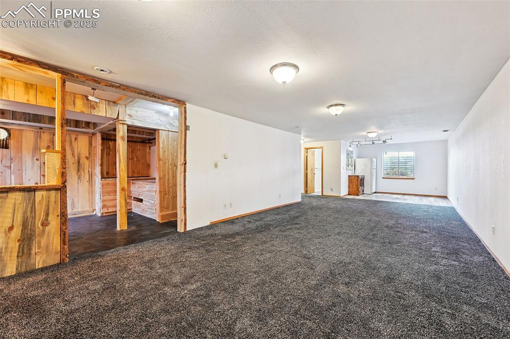 Image 29 of 50: Unfurnished living room featuring dark colored carpet and baseboards