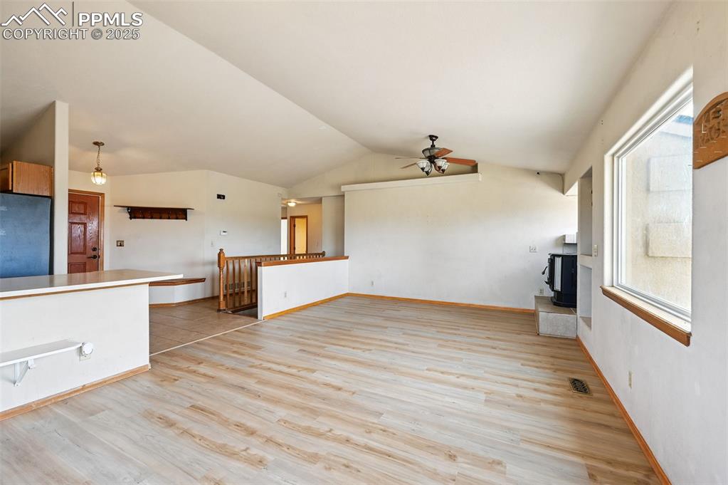 Image 5 of 50: Unfurnished living room with light wood finished floors, vaulted ceiling, a