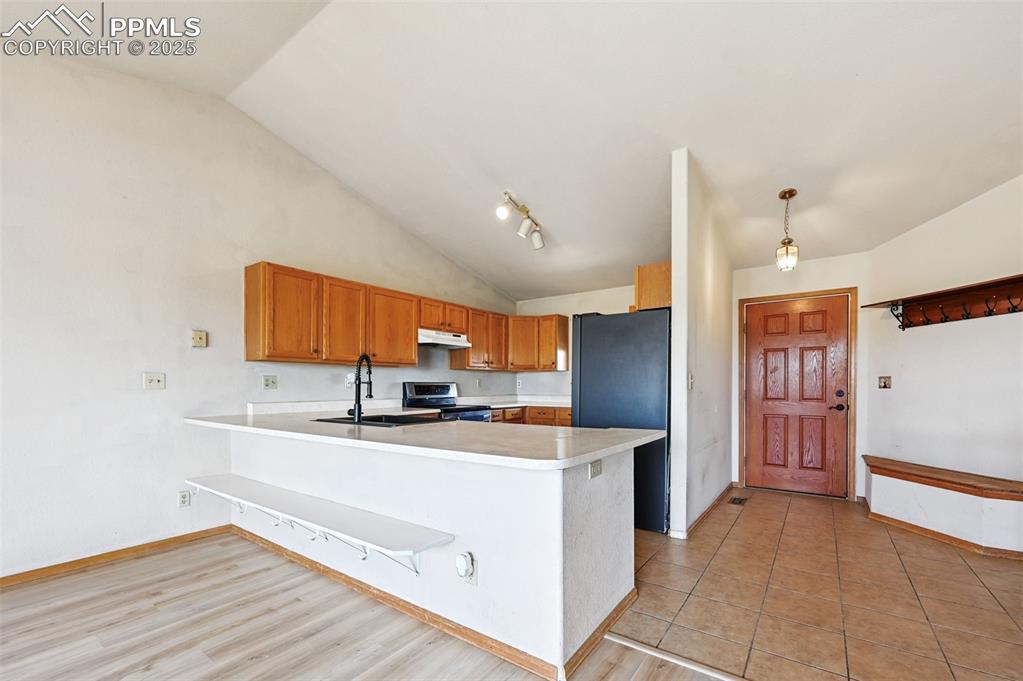 Image 9 of 50: Kitchen featuring light countertops, a peninsula, freestanding refrigerator