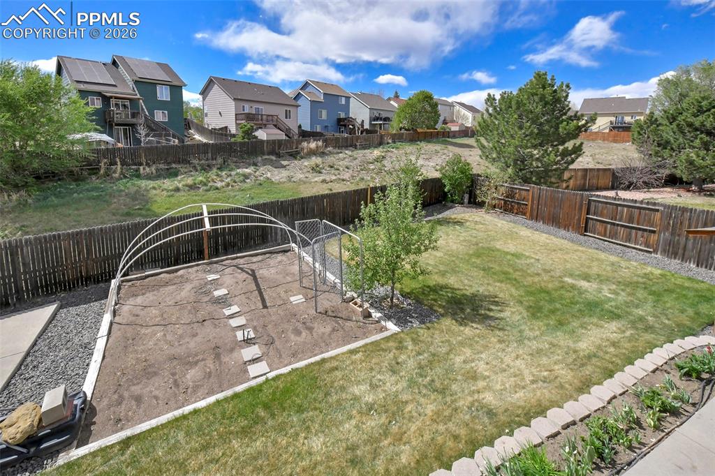 Image 37 of 46: Expansive backyard featuring a lush lawn, dedicated garden area with a hoop