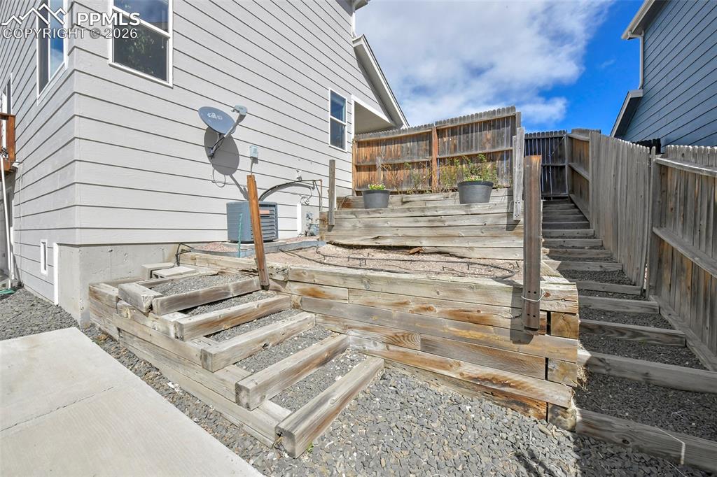 Image 38 of 46: Terraced side yard for gardening with wood retaining walls and steps
