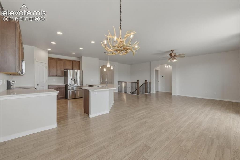 Image 13 of 50: Open-concept living space with wood-finish flooring, a contemporary antler-