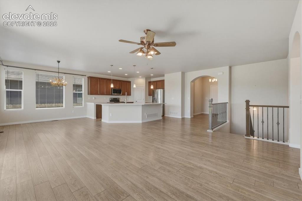 Image 17 of 50: Open dining area featuring light wood-finish flooring and a prominent antle