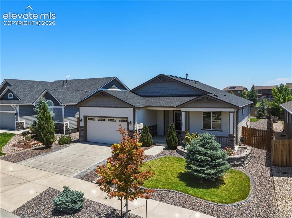 Image 2 of 50: Single-story residence featuring a two-car garage, stone facade accents, an