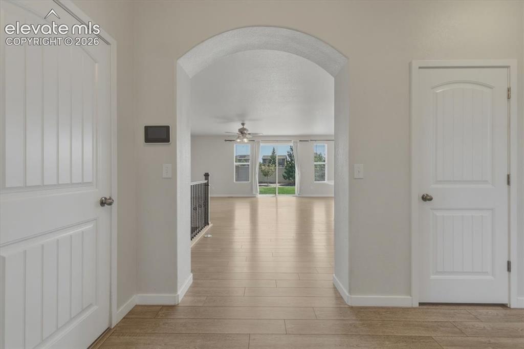 Image 4 of 50: Arched entryway leading to an open living area featuring wood-finish floori