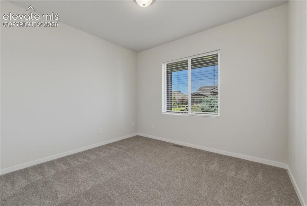 Image 6 of 50: Carpeted room with neutral walls, featuring a window with white blinds