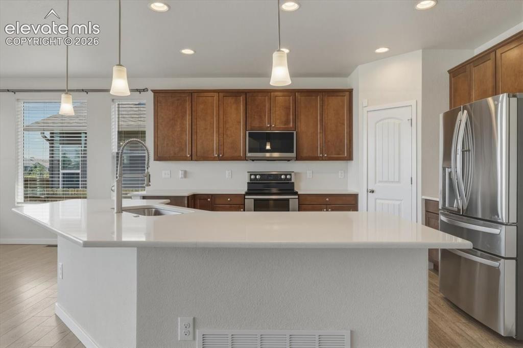 Image 9 of 50: Kitchen featuring a large central island with a sink and pendant lighting,