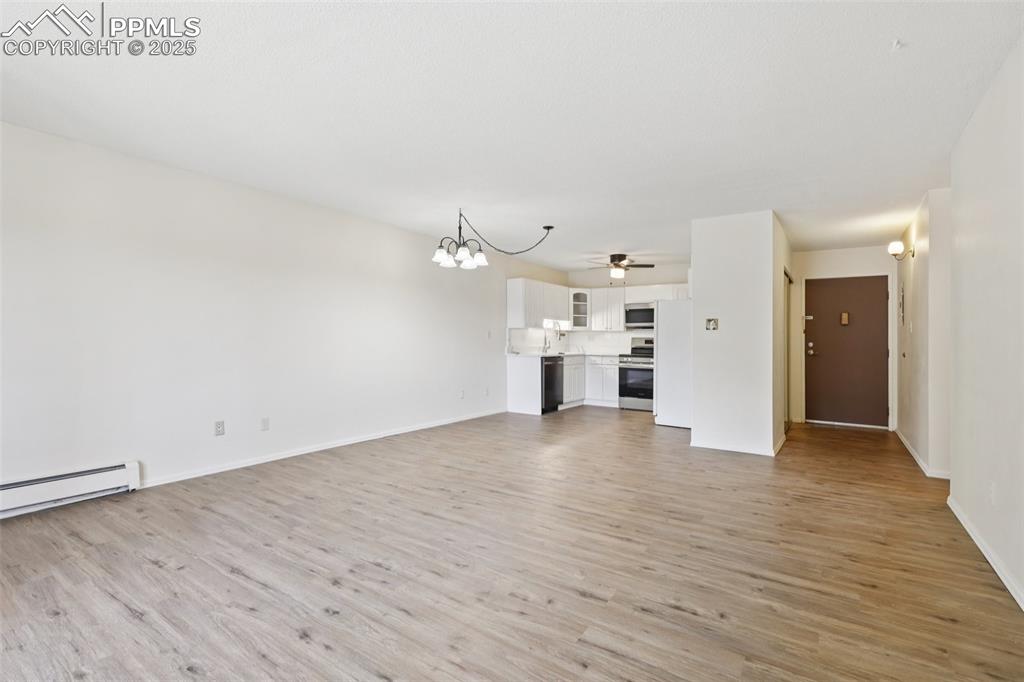 Image 10 of 25: Unfurnished living room with a chandelier, light wood finished floors, and