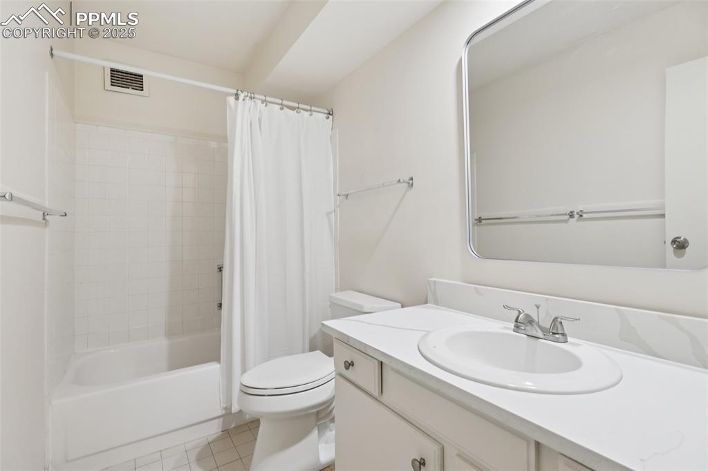 Image 13 of 25: Full bathroom featuring vanity, shower / bath combo with shower curtain, an