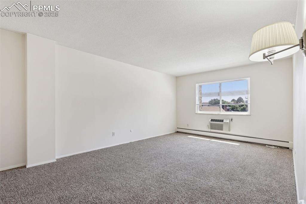 Image 17 of 25: Spare room with baseboard heating, carpet, and a wall mounted AC