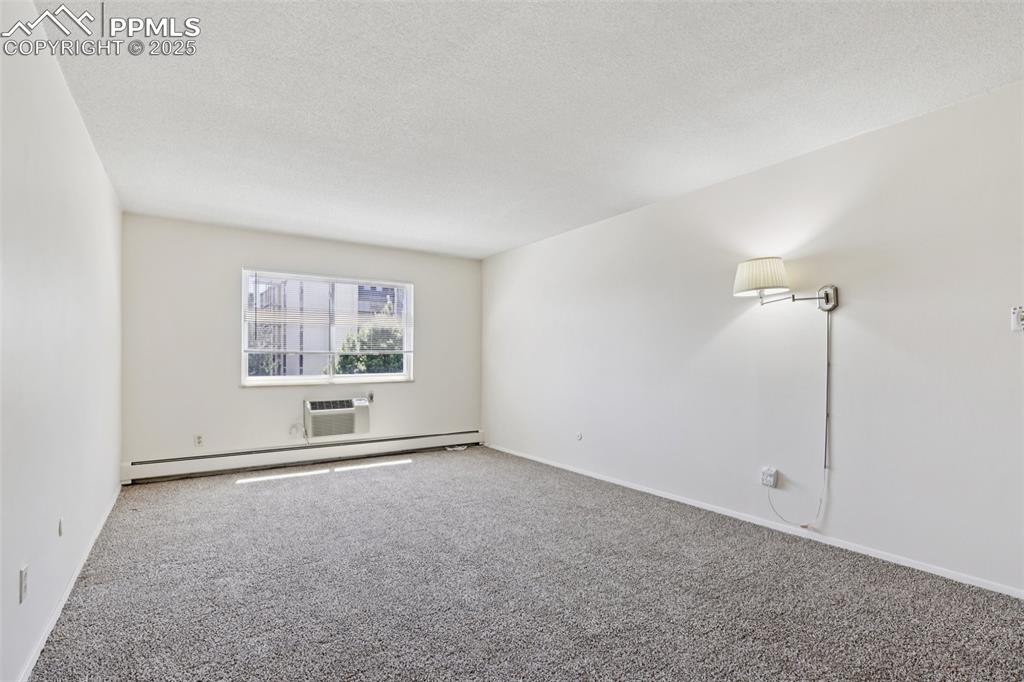 Image 18 of 25: Carpeted spare room featuring baseboard heating, a textured ceiling, and an