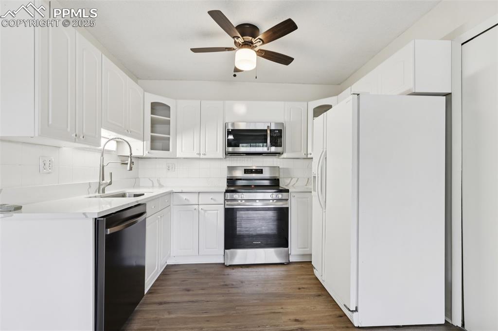Image 2 of 25: Kitchen with stainless steel appliances, tasteful backsplash, glass insert