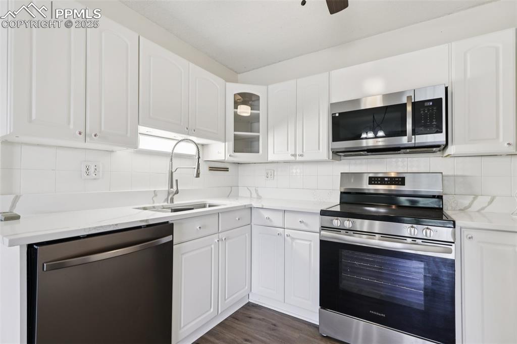 Image 3 of 25: Kitchen with stainless steel appliances, decorative backsplash, glass inser
