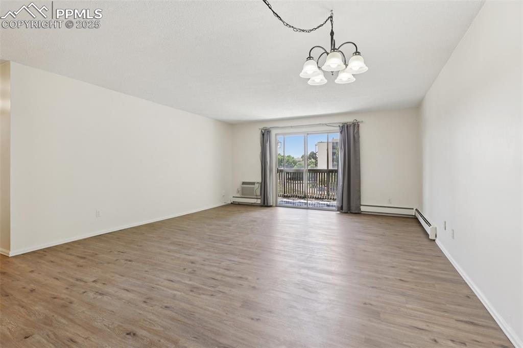 Image 7 of 25: Unfurnished room with a chandelier and wood finished floors