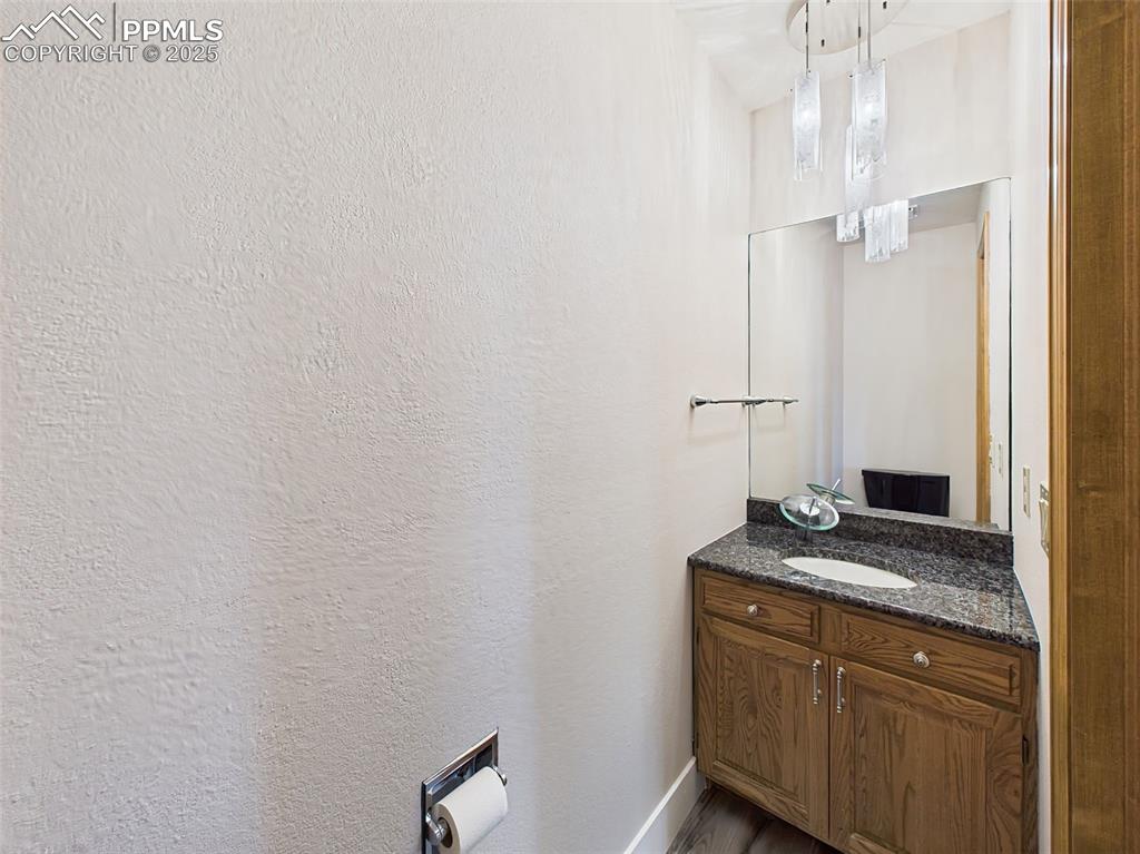 Image 21 of 50: 1/2 Bath on Main Level with granite countertop, modern light fixture and wa