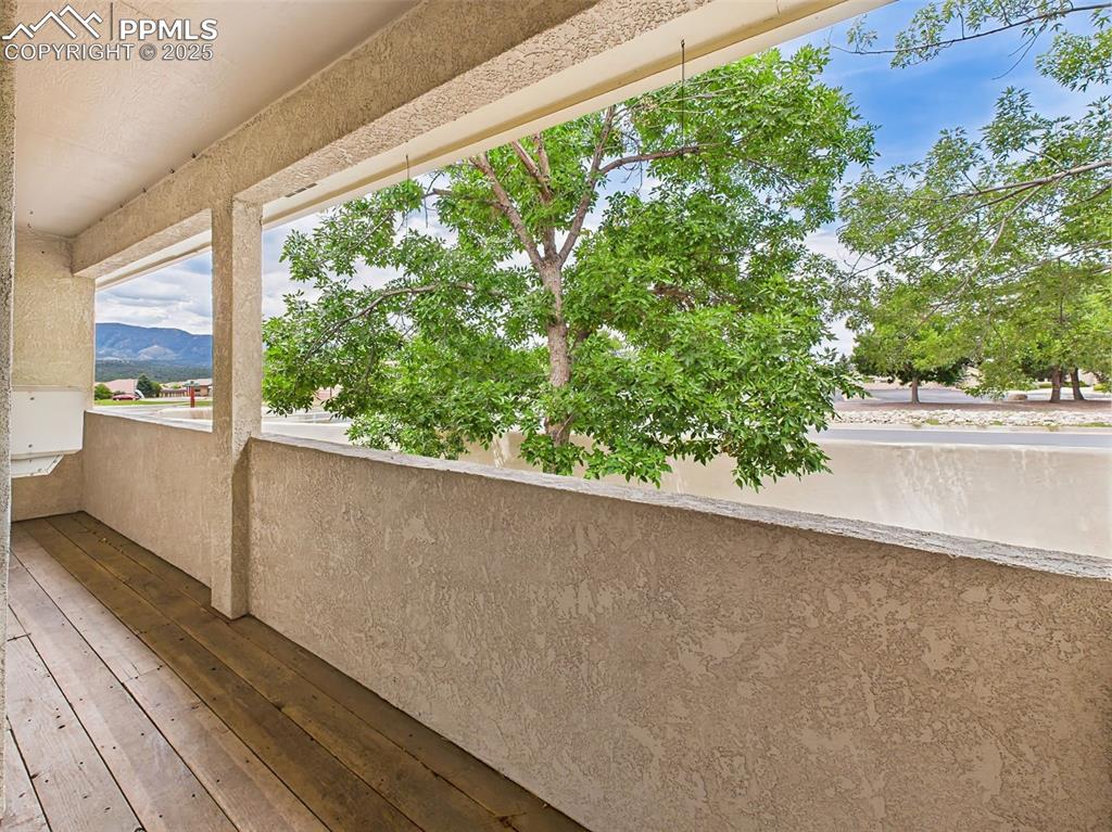 Image 26 of 50: Covered deck/balcony with a mountain view. The lush tree offers privacy and