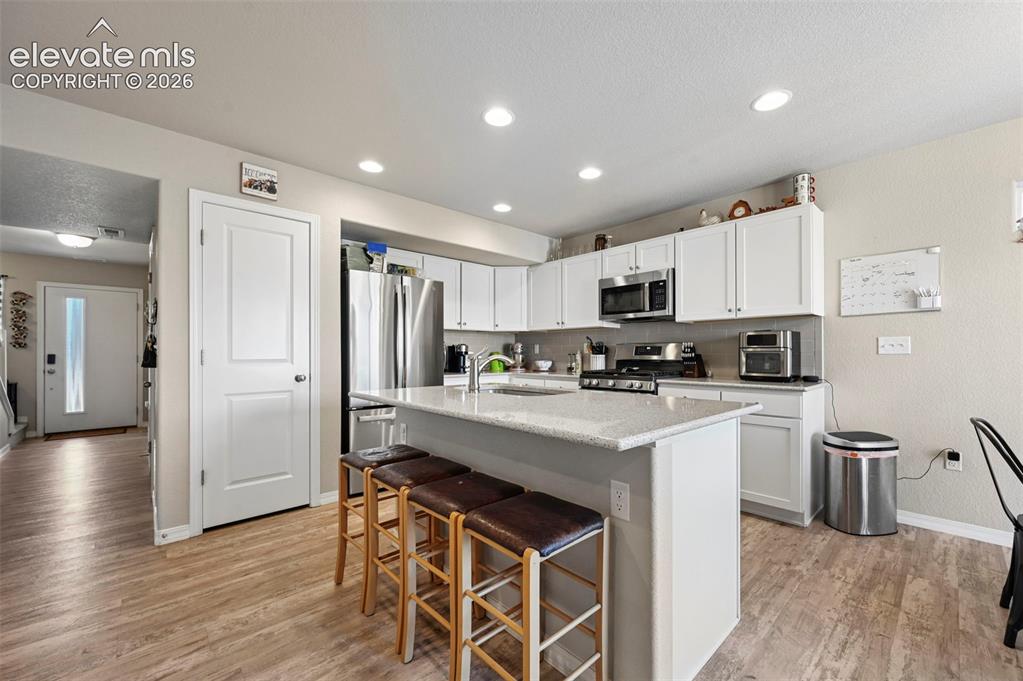 Image 3 of 30: Contemporary kitchen featuring white cabinetry, stainless steel appliances,