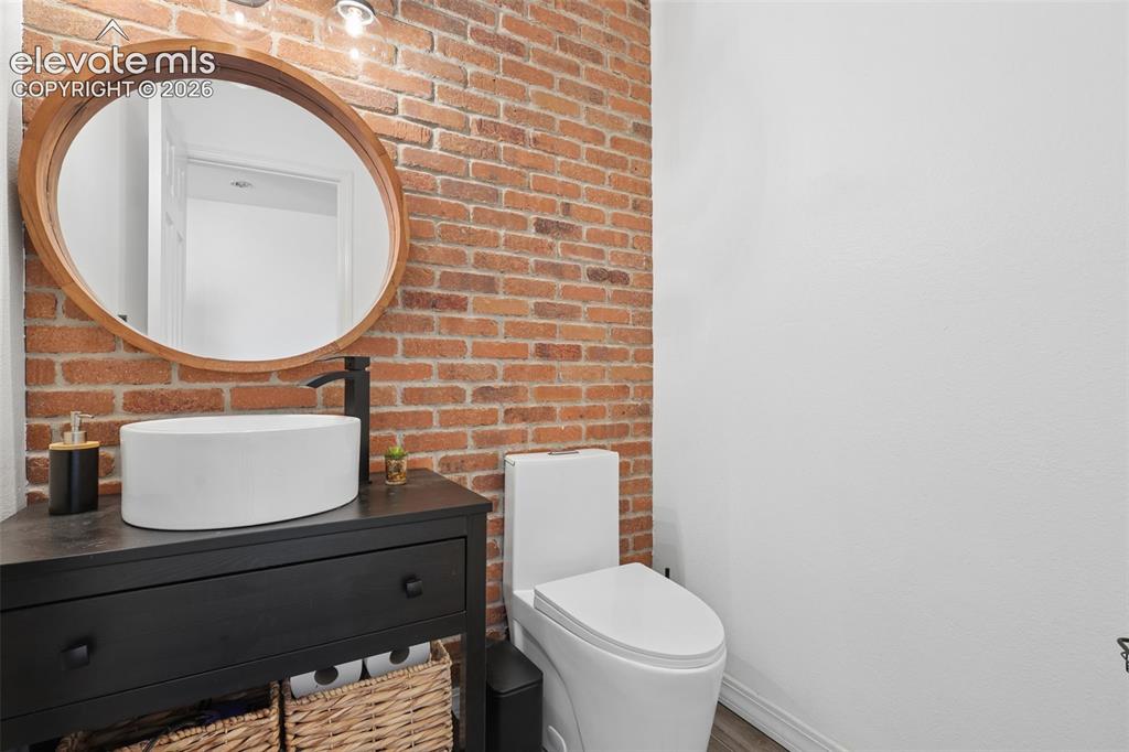Image 10 of 27: Half-powder bath on  main with brick wall accent