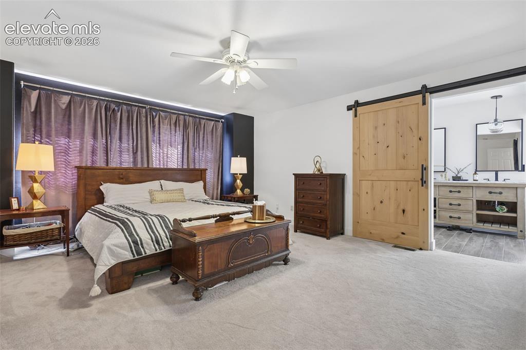 Image 18 of 27: primary bedroom upper level with barn door leading into bathroom