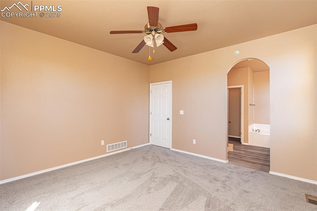 Image 15 of 41: Carpeted spare room featuring arched walkways and a ceiling fan