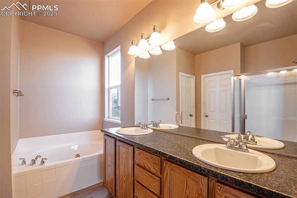 Image 16 of 41: Full bathroom featuring double vanity, a jetted tub, dark wood-style floori