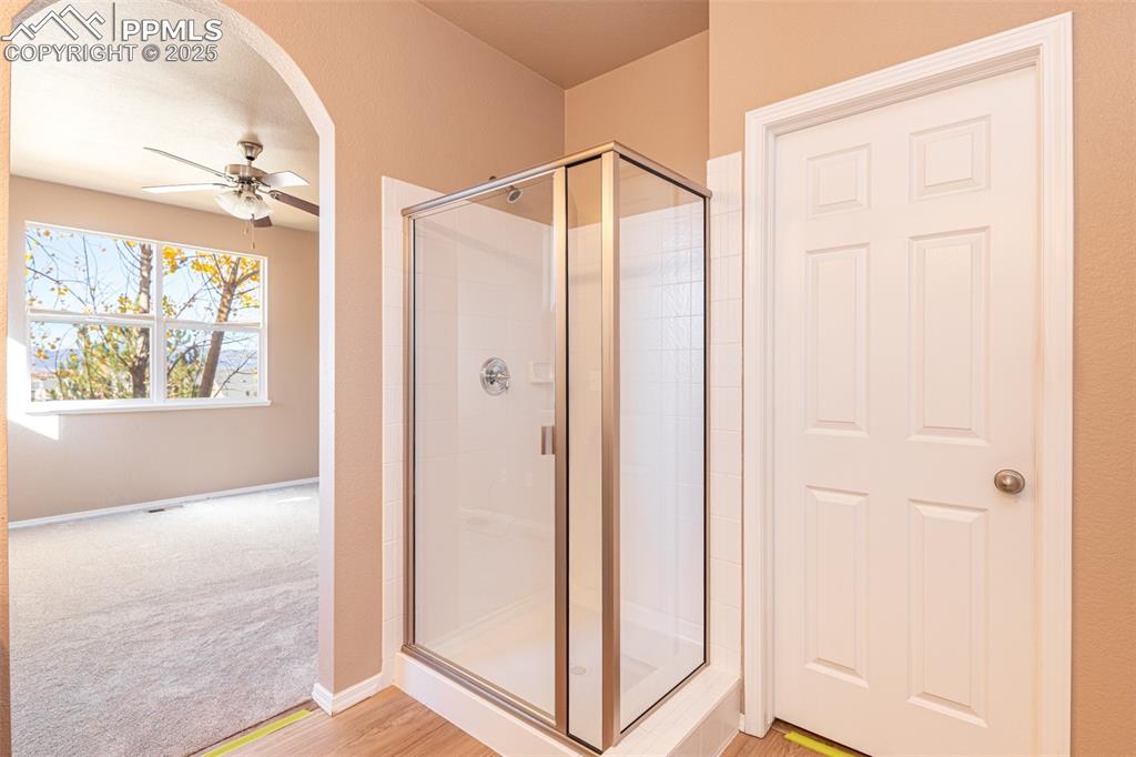 Image 17 of 41: Bathroom featuring a ceiling fan, a stall shower, wood finished floors, and