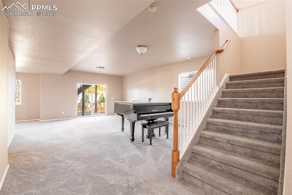 Image 19 of 41: Sitting room with a textured ceiling, carpet flooring, and stairway