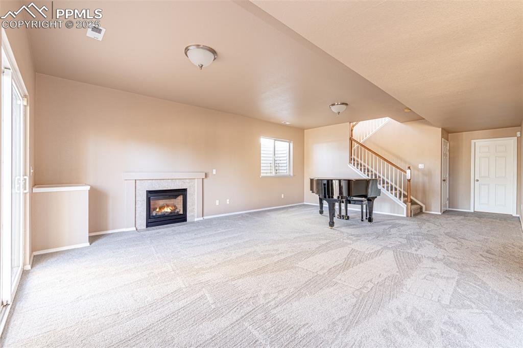 Image 21 of 41: Unfurnished living room featuring light colored carpet, a fireplace, and st