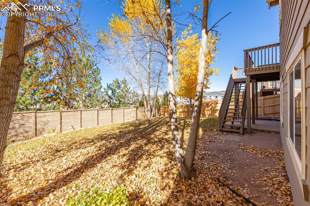Image 37 of 41: Fenced backyard with stairs and a deck