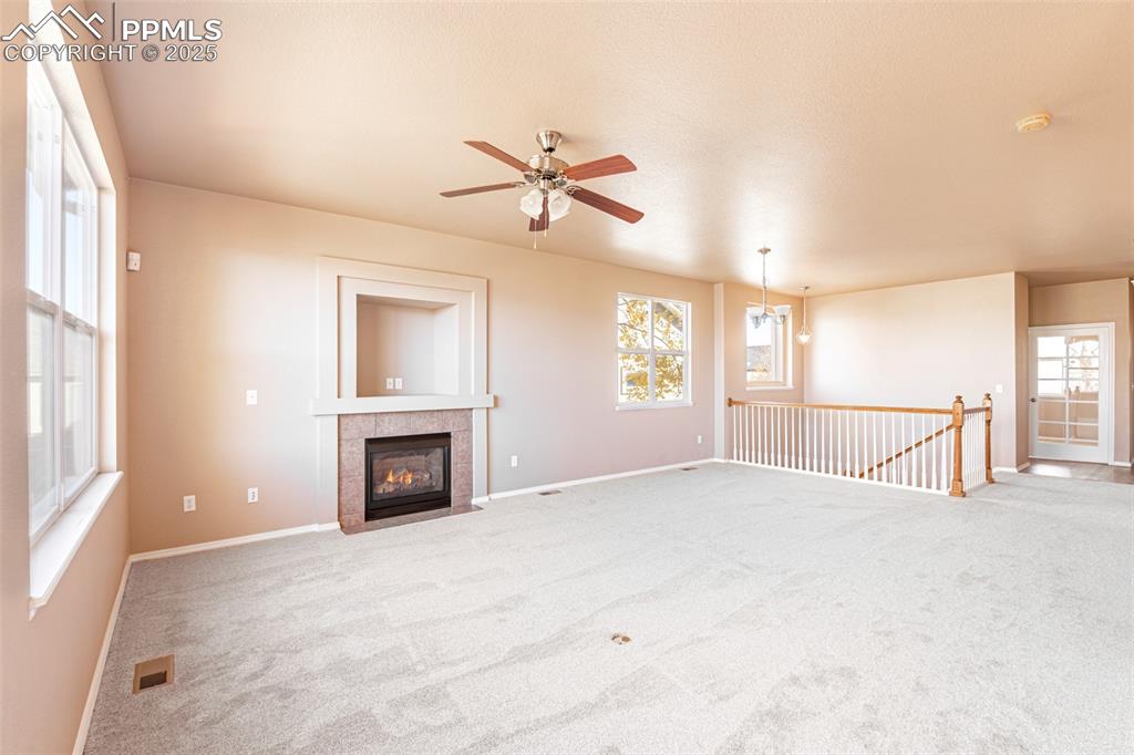 Image 5 of 41: Unfurnished living room featuring carpet, a tiled gas fireplace, a ceiling 