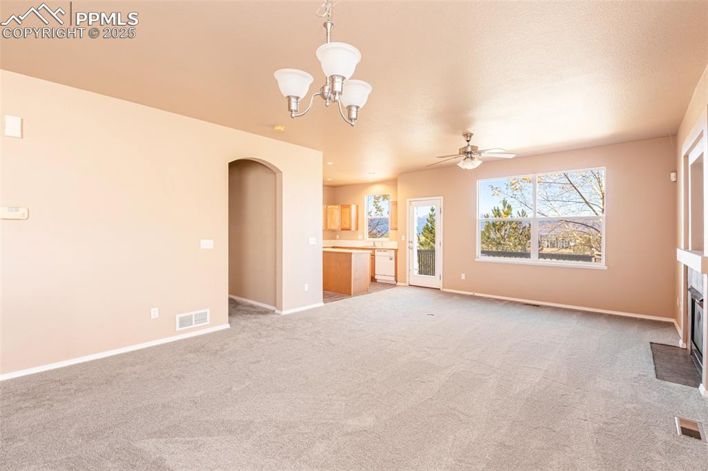 Image 6 of 41: Unfurnished living room with light colored carpet, arched walkways, a firep