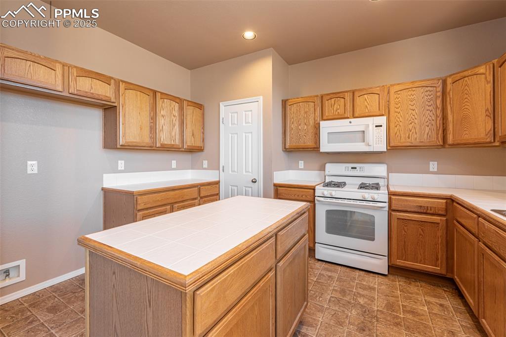 Image 7 of 41: Kitchen featuring white appliances, tile countertops, and recessed lighting