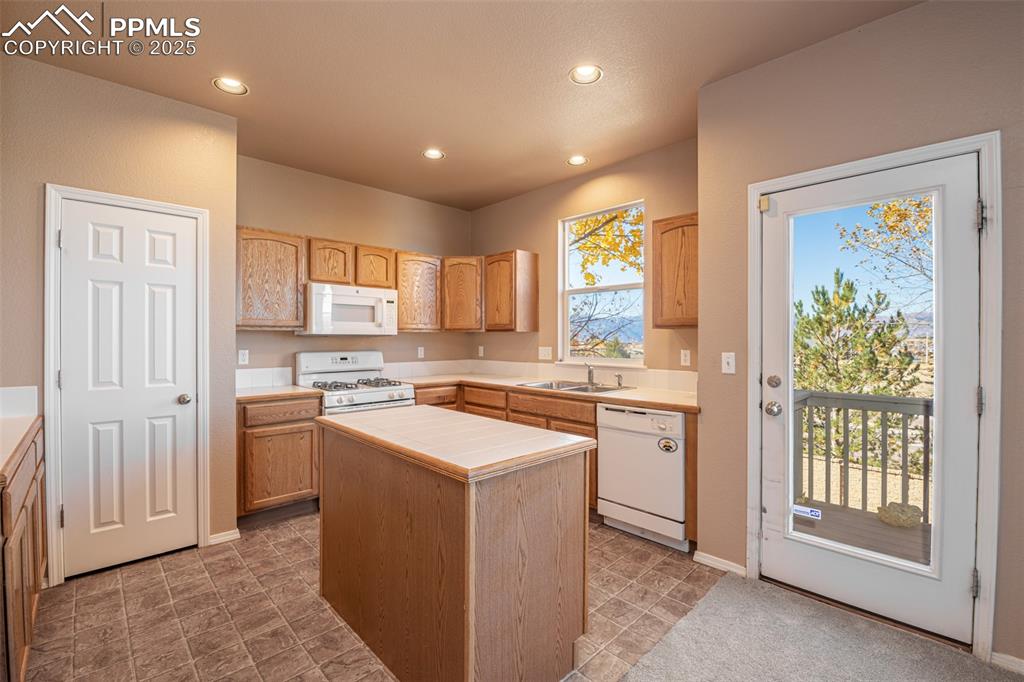 Image 8 of 41: Kitchen with recessed lighting, white appliances, a center island, tile cou