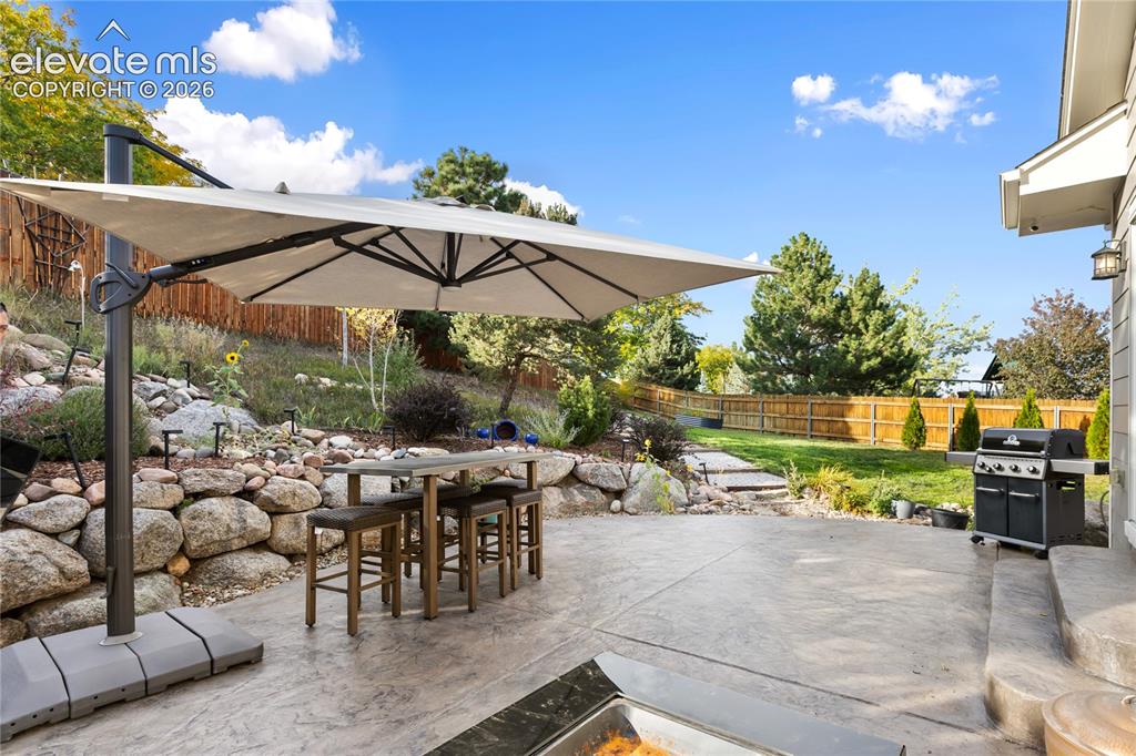 Image 11 of 38: Expansive concrete patio with a stone retaining wall, terraced landscaping,