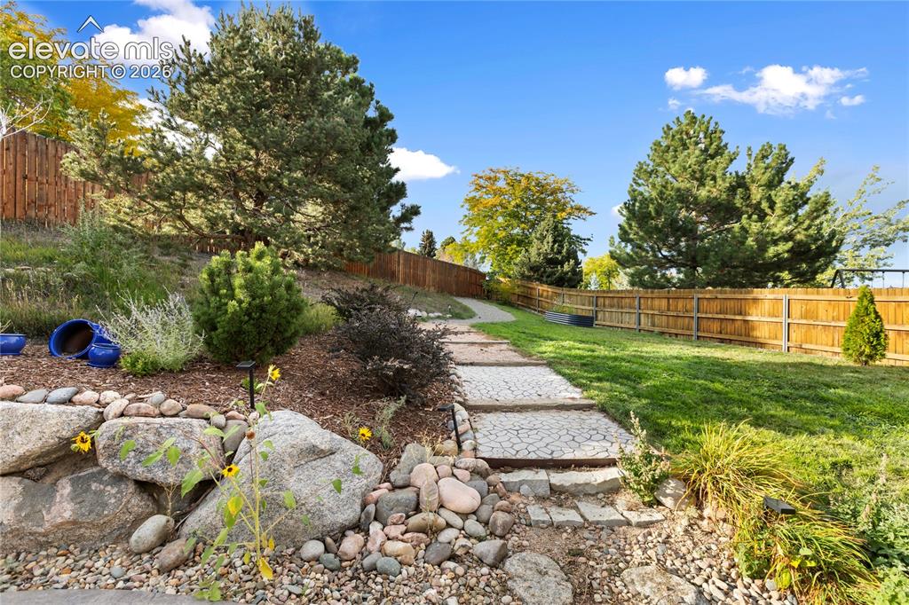 Image 12 of 38: Expansive backyard featuring a manicured lawn, established landscaping, a s