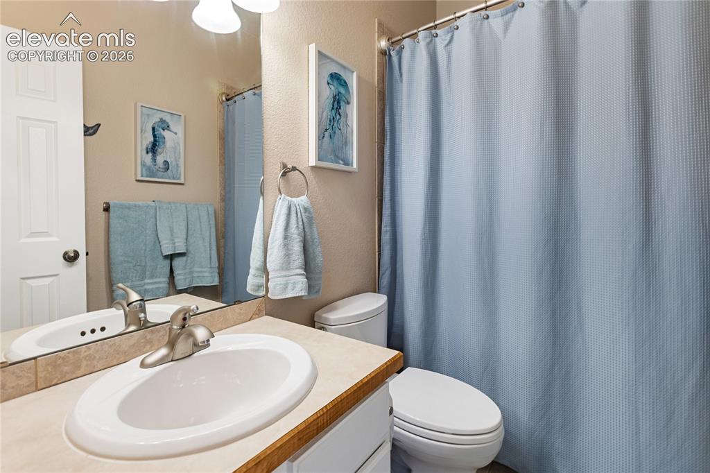 Image 16 of 38: Bathroom featuring a vanity with an integrated sink, a large mirror, a toil