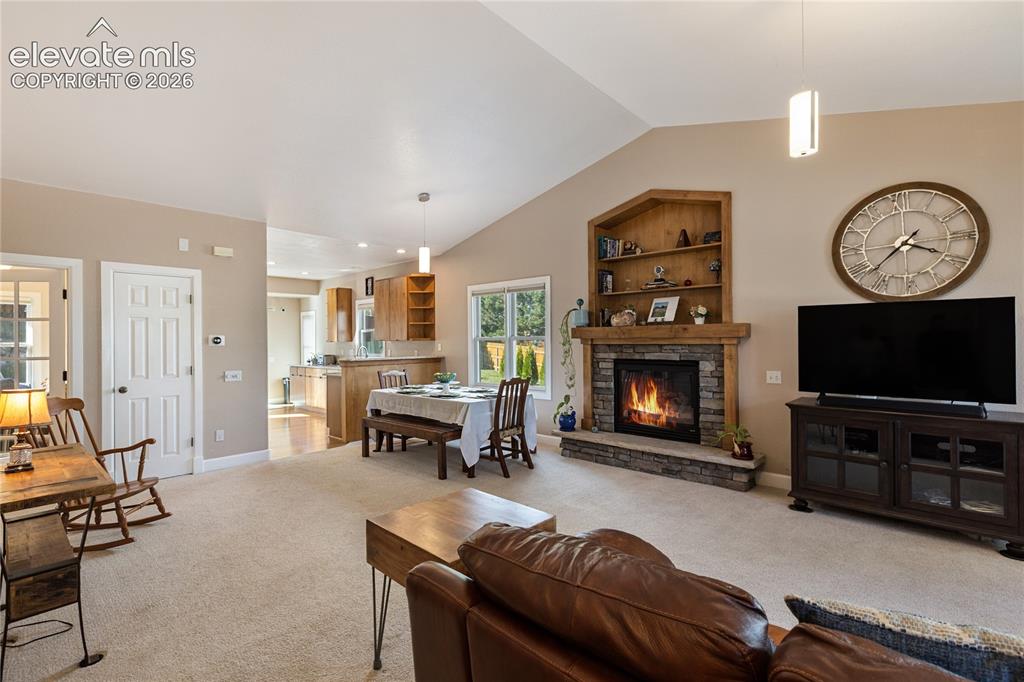 Image 2 of 38: Vaulted ceiling, stone-surround fireplace with wood mantel, built-in shelvi