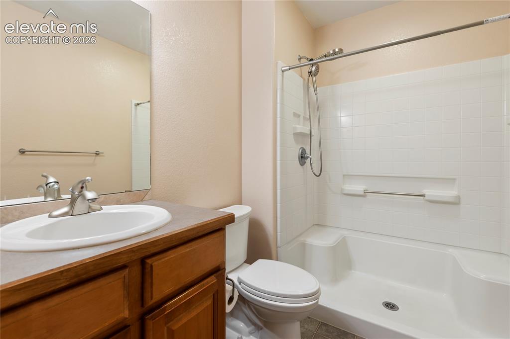 Image 21 of 38: Wood-finish vanity with a drop-in sink, brushed nickel faucet, and a combin