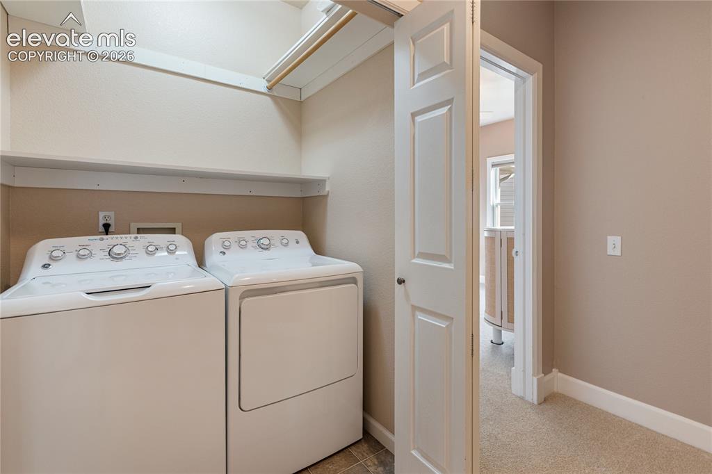Image 28 of 38: Dedicated laundry area featuring a shelf, hanging rod, and tile flooring
