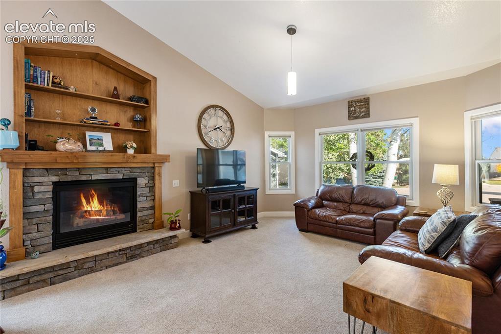 Image 3 of 38: Stone-surround fireplace with a wood mantle and built-in shelving, vaulted 