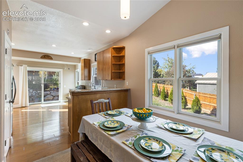 Image 32 of 38: Vaulted ceiling with recessed lighting, wood-finish flooring, sliding glass