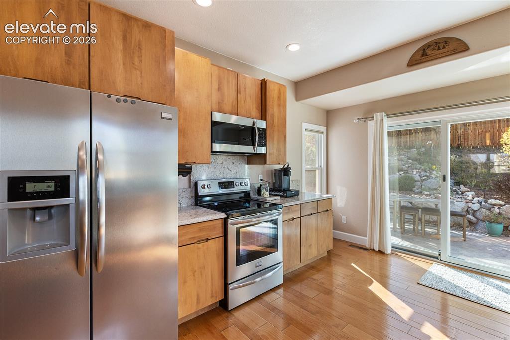 Image 33 of 38: Stainless steel appliance suite, wood-finish cabinetry, light-toned counter