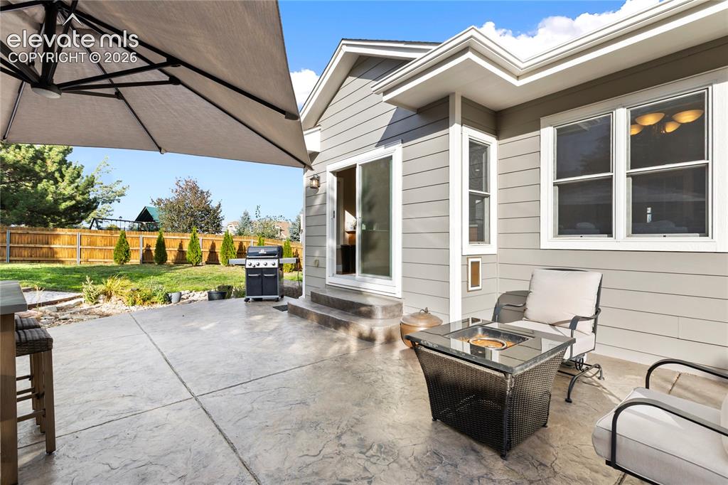 Image 34 of 38: Expansive stamped concrete patio with direct access to the backyard and a s