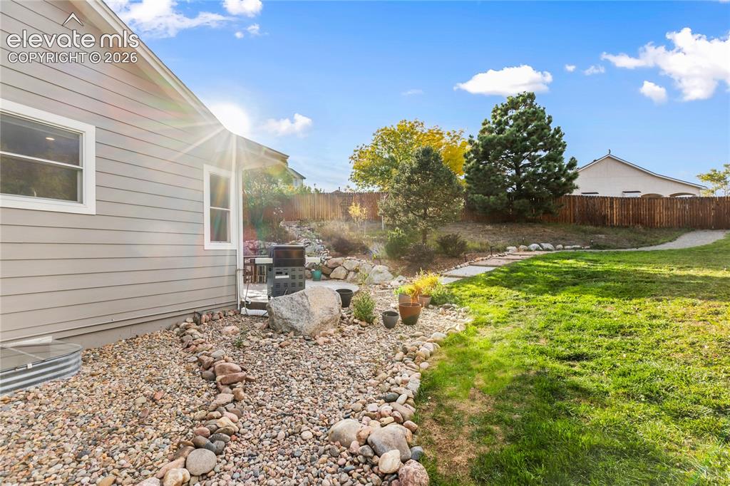 Image 36 of 38: Expansive backyard featuring a manicured lawn, established landscaping, and