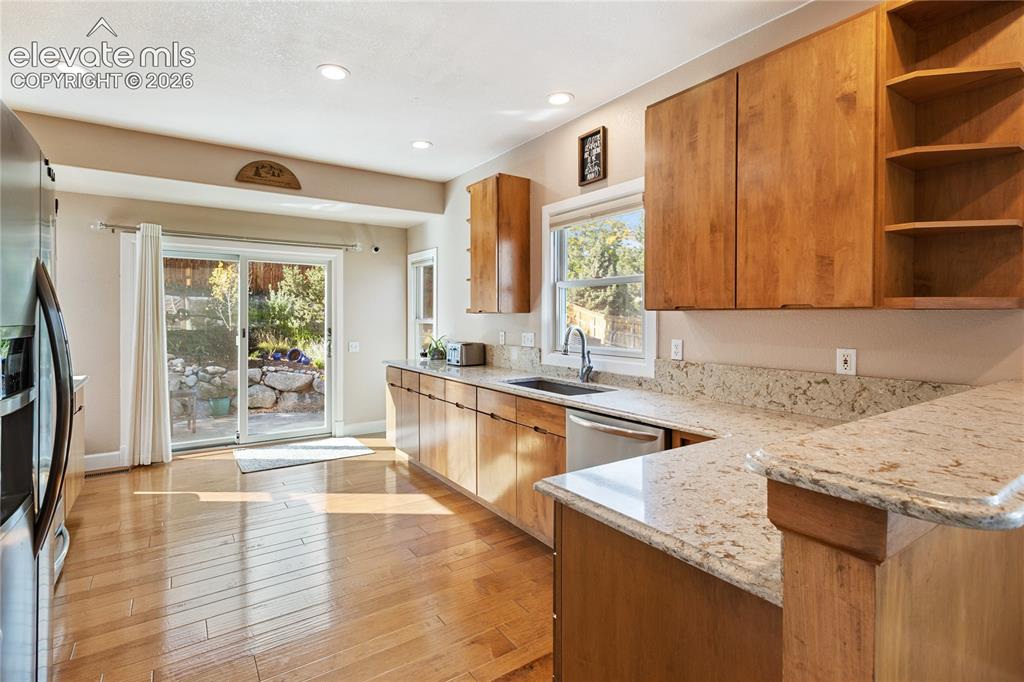 Image 4 of 38: Wood-finish flooring, recessed lighting, wood cabinetry, stone countertops,