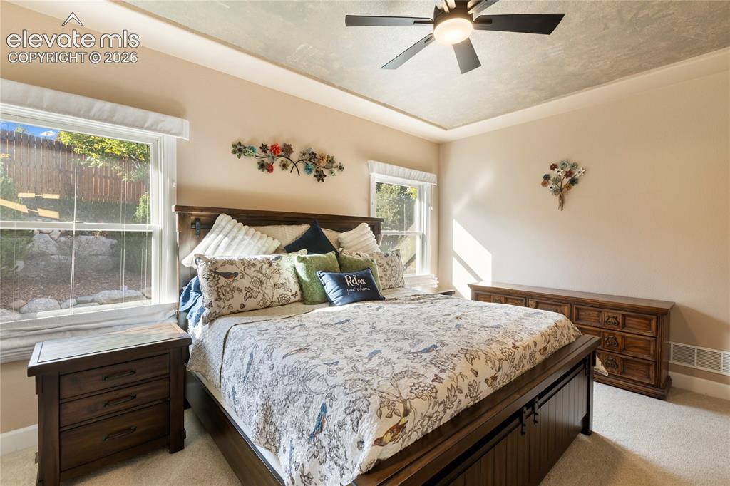 Image 7 of 38: Recessed ceiling with a ceiling fan, two windows, and neutral wall paint