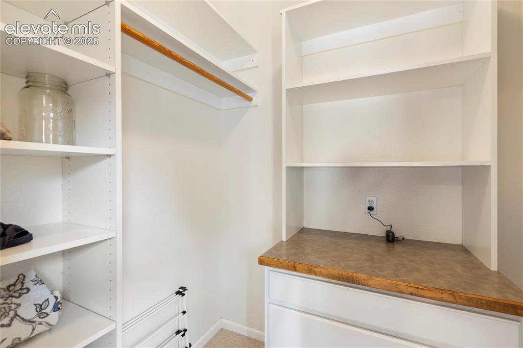Image 8 of 38: Custom closet system featuring white shelving units, a natural wood-finish 