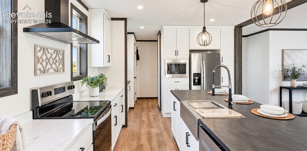 Image 2 of 6: Kitchen featuring white cabinetry, a center island with a stainless steel f